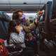 Three passengers sit on an airplane wearing surgical masks.